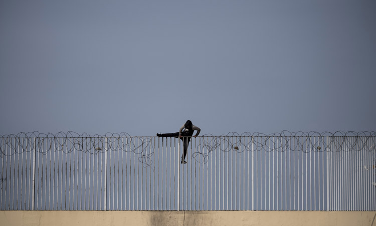 Un menor trata de cruzar la cerca de Melilla. Foto: ACN - Pedro Armestre / Save the Children